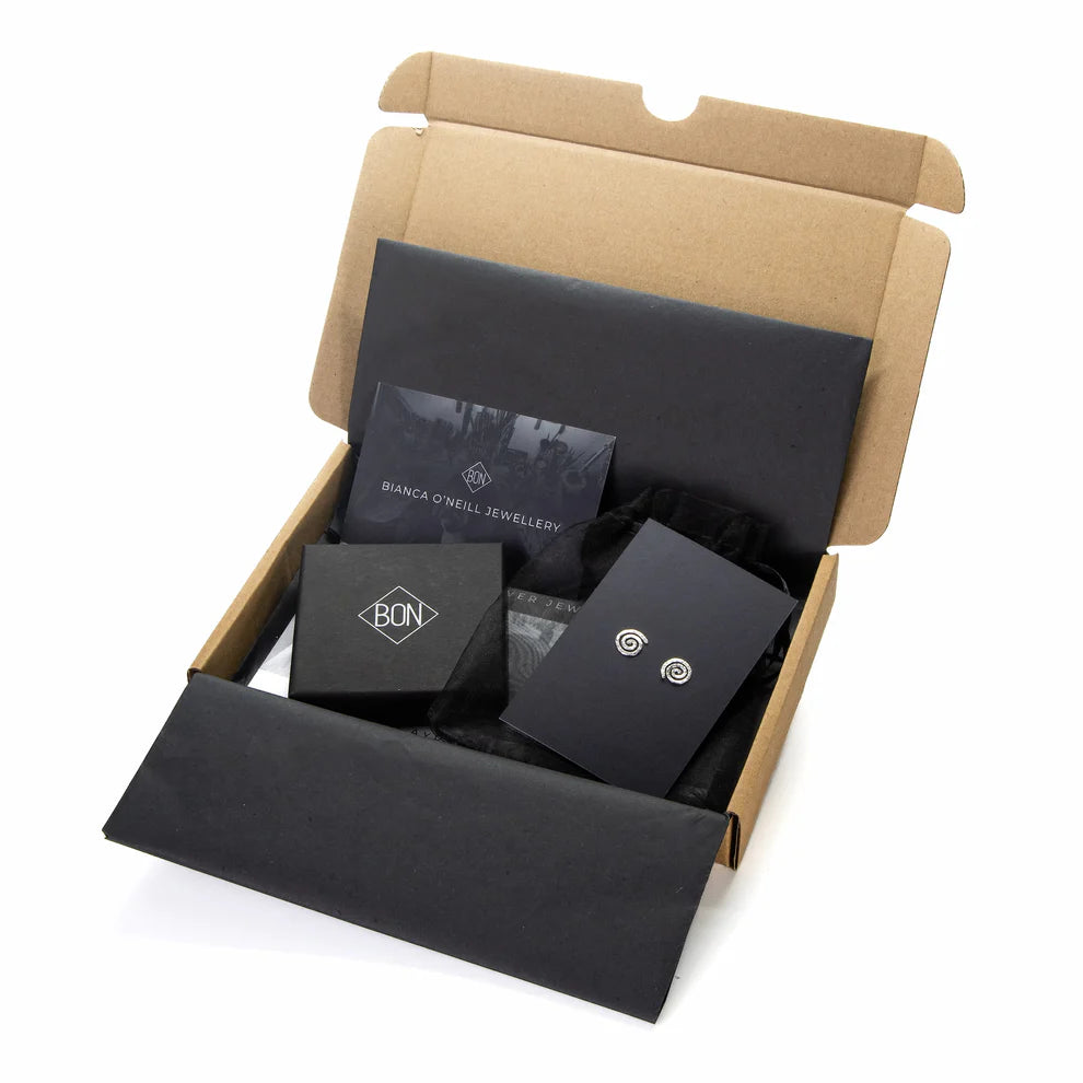 Open cardboard box containing black jewelry boxes with visible branding on a white background
